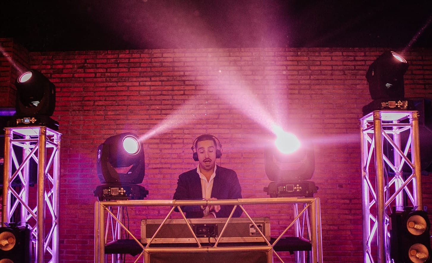 Montaje de noche con moving heads en torres y luz magenta sobre pared de ladrillo
