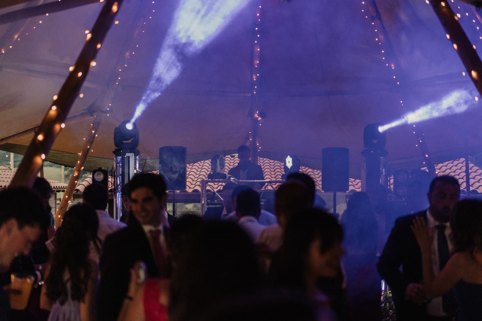 Carpa de boda con guirnaldas y haces de luz sobre la pista llena
